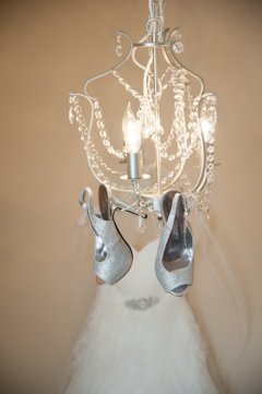 brides silver shoes hanging from chandelier wedding dress in background durango portrait studio