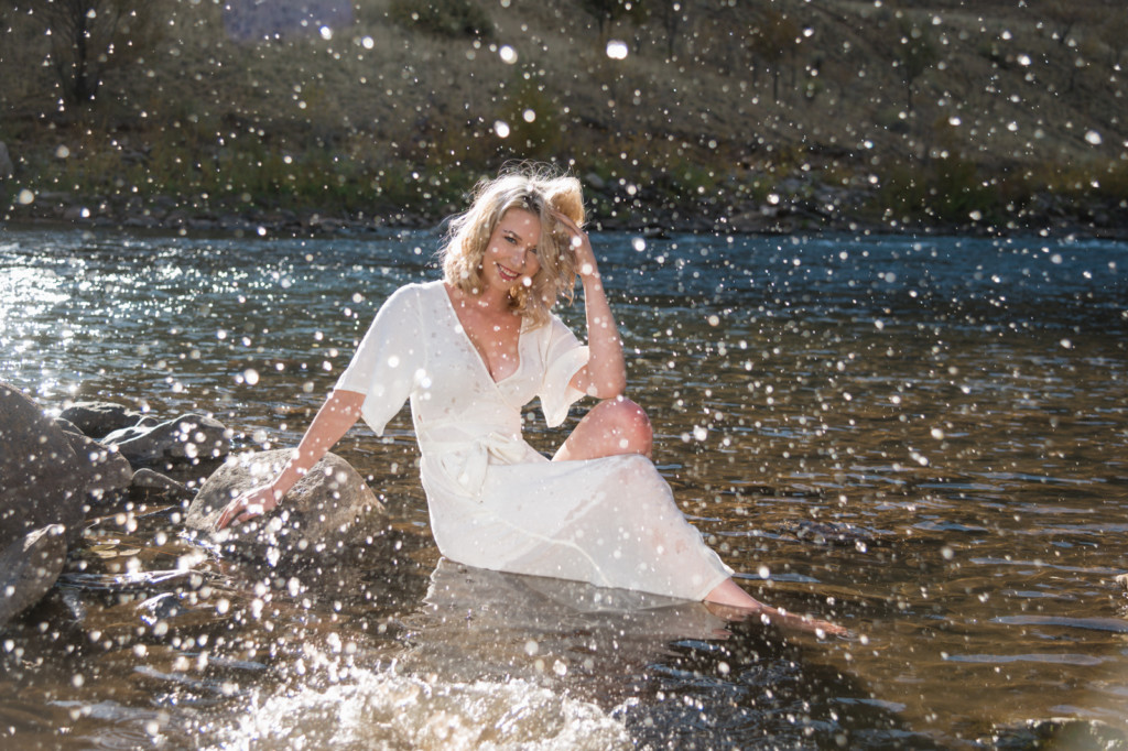 senior girl in river with water splashing photo