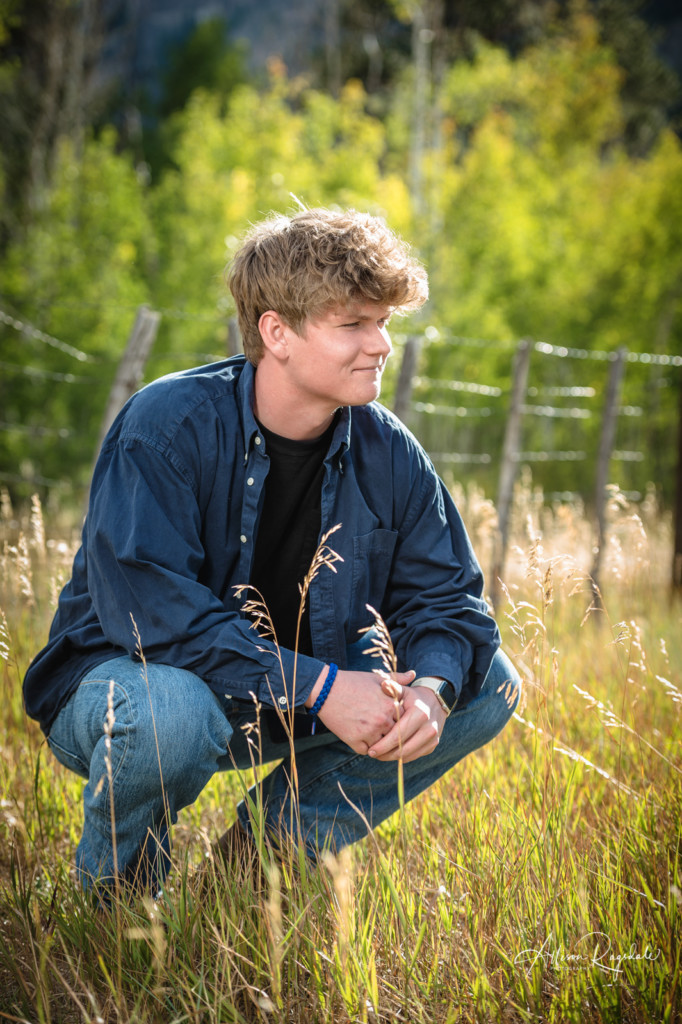 senior guy crouching in long grass picture