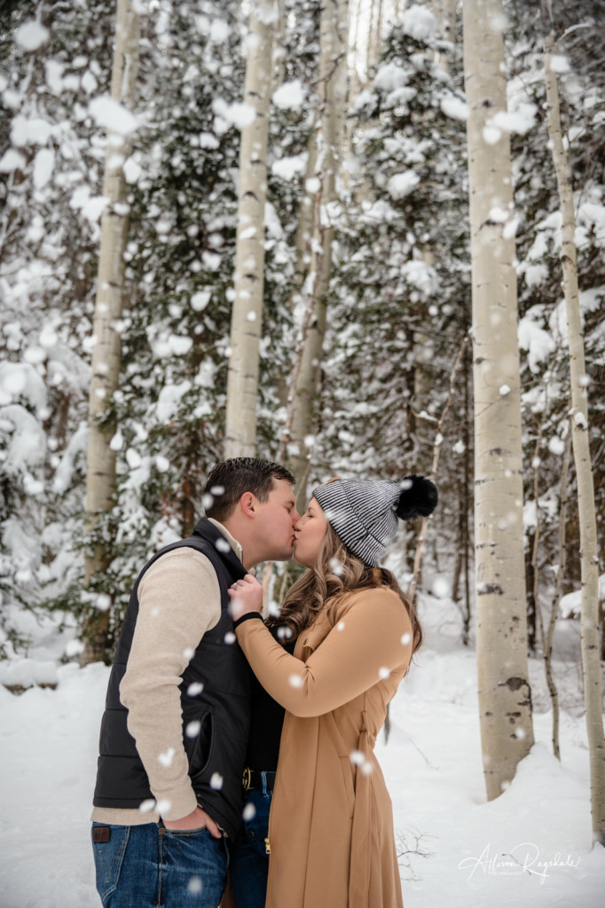 couple kiss in the snowy forest colorado portrait