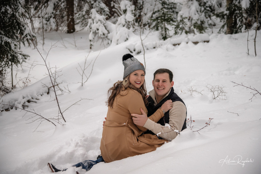 couple sitting in snow engagement portrait