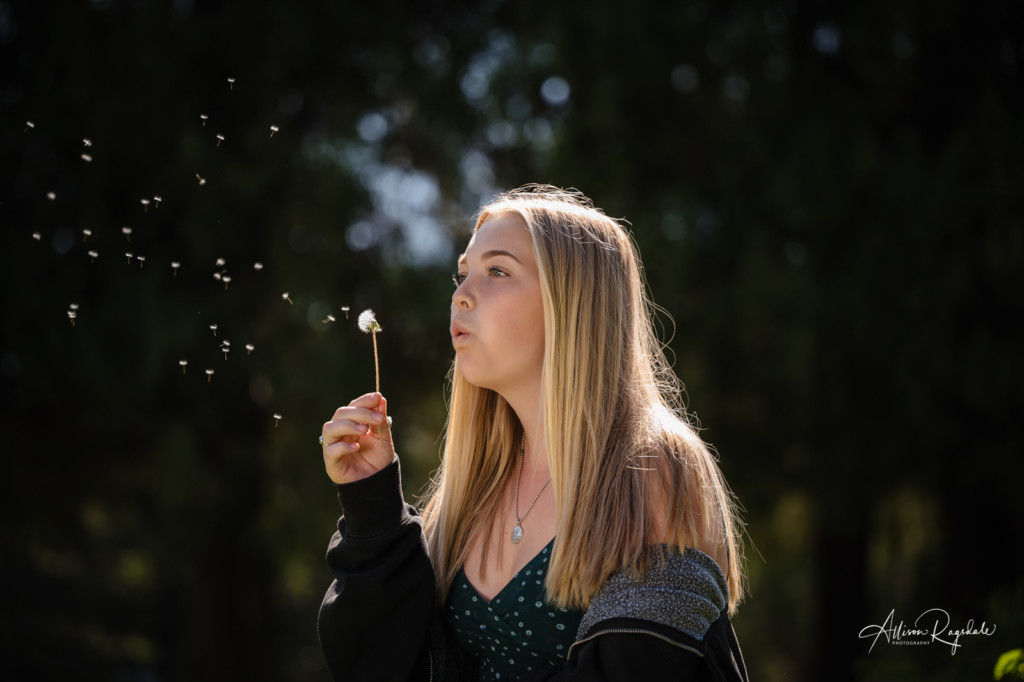 senior pic girl blowing on dandelion