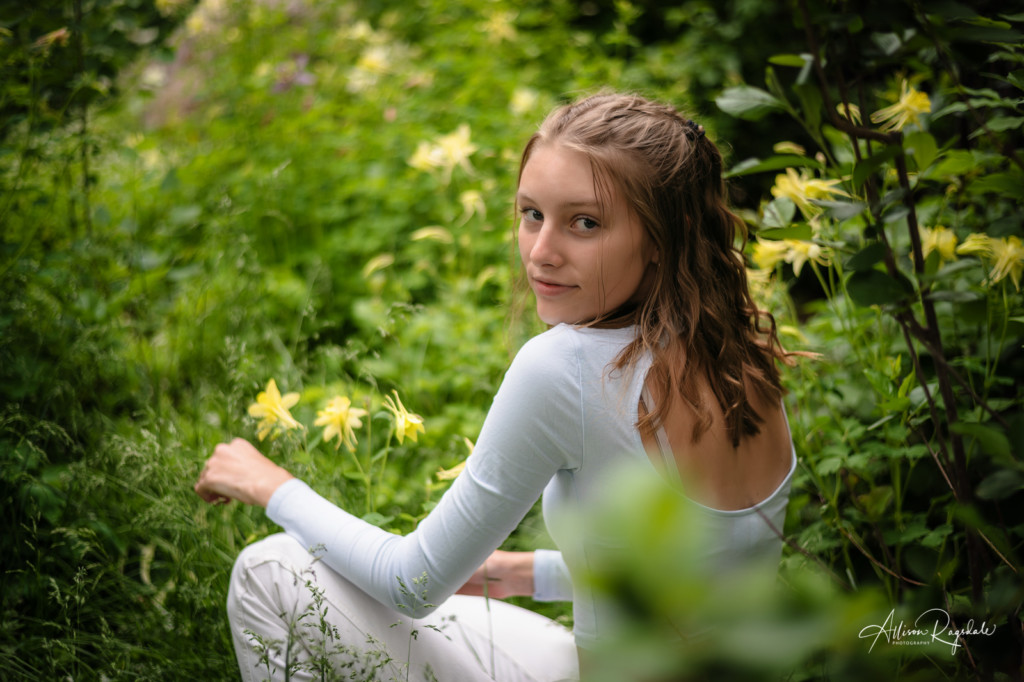 anna over the shoulder with yellow columbine flowers senior picture