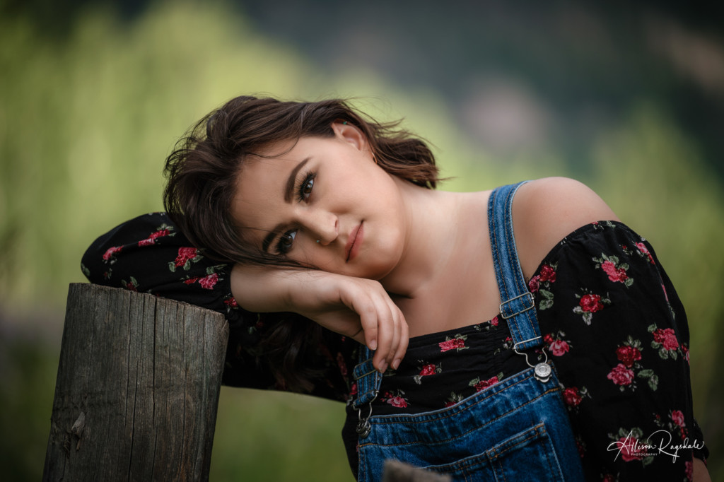 senior photo with rustic fence and overalls