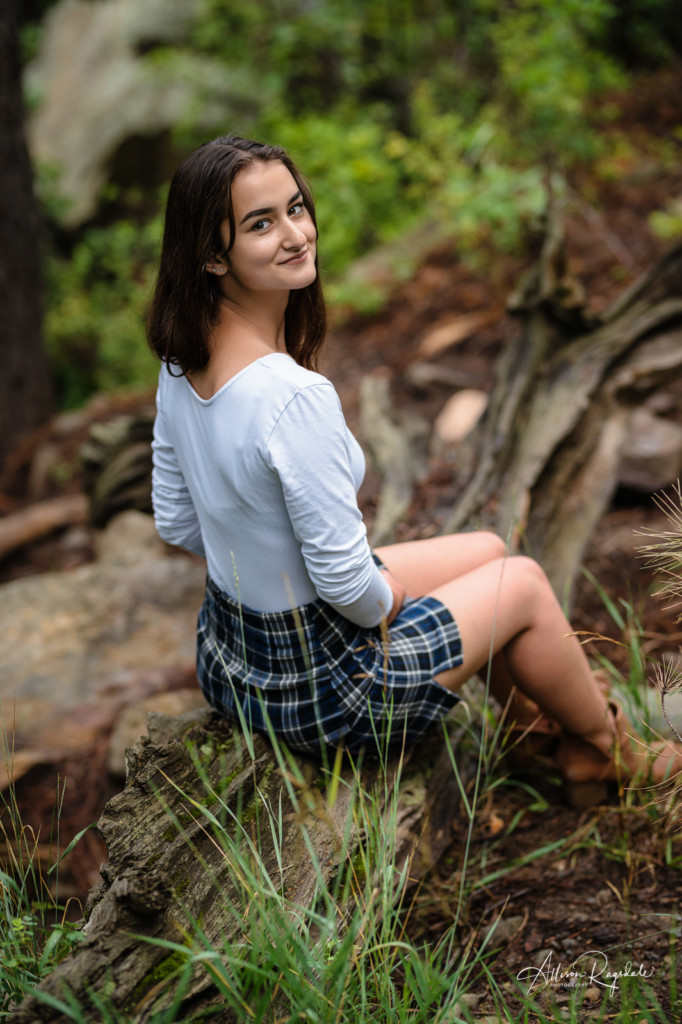 senior picture sitting on log plaid skirt