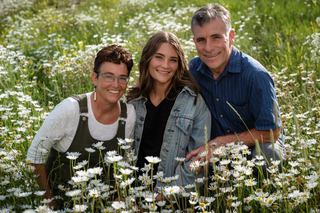 parents and daughter photo sitting in daisies