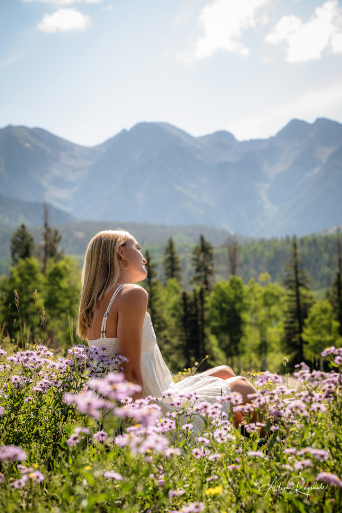 senior girl in white dress with purple flowers and mountains
