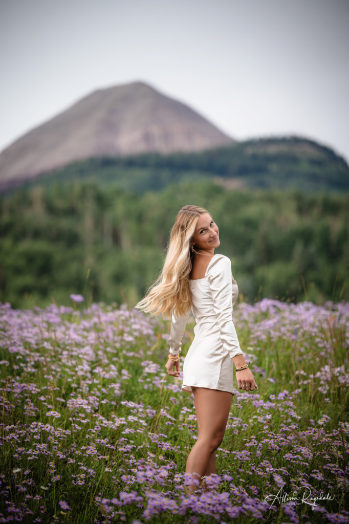 senior pic hair flip wildflowers and mountains