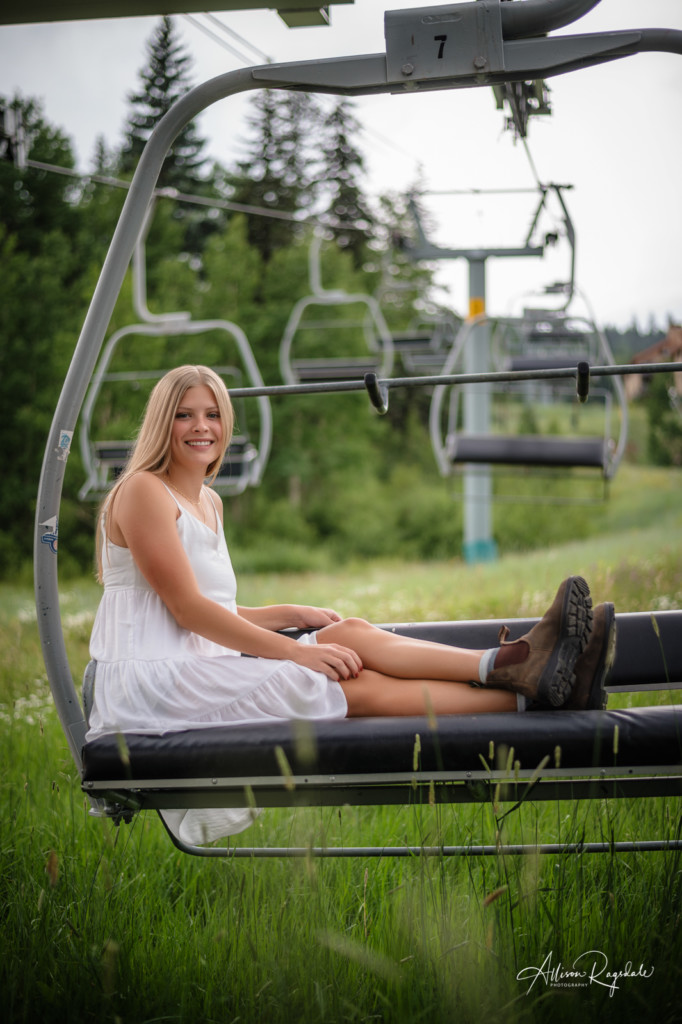 girl in white dress on ski lift at purgatory senior photo