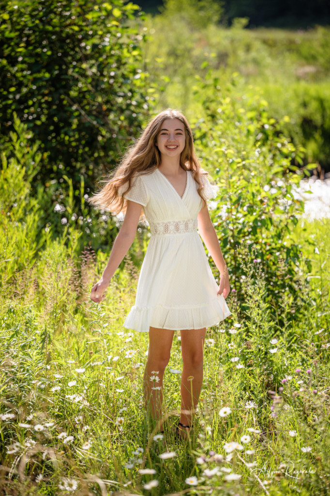 girl senior picture spinning in white dress in white daisies