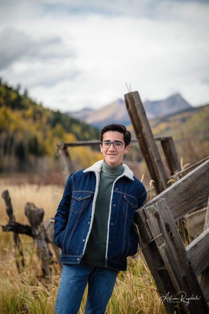 senior guy leaning on fence colorado mountain background picture