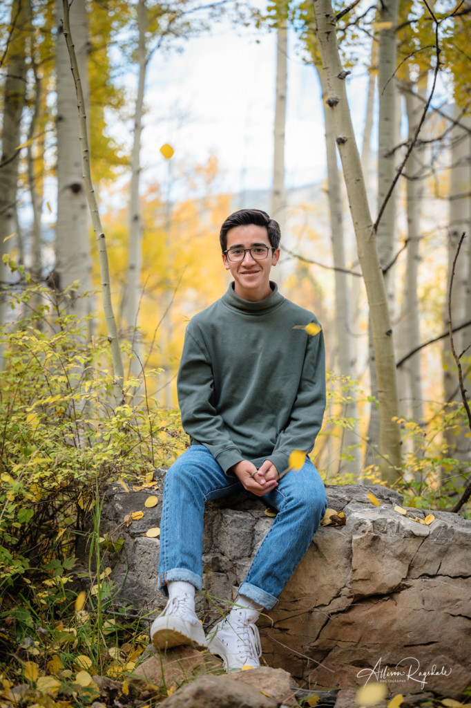 senior guy photo sitting on rock in yellow aspens in fall