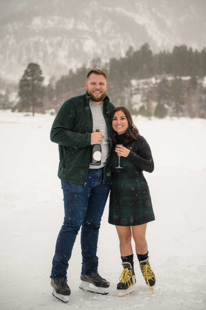 surprise proposal on ice skates couple celebrating with champagne portrait